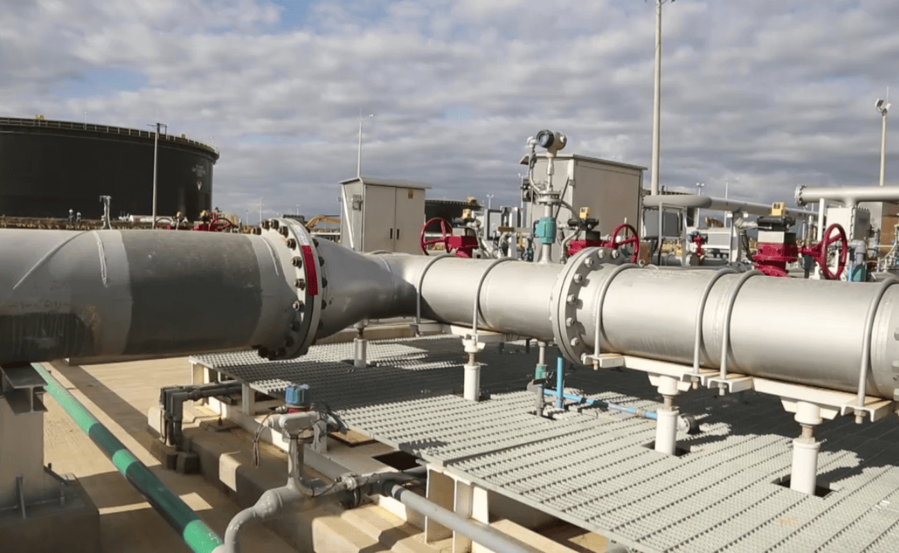 Piping and valves of a pumping system next to a storage tank