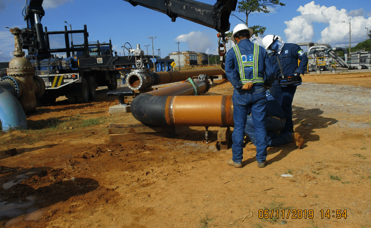 Lifting a pipe section with a crane at an industrial facility